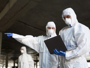 An image of people in hazmat suits looking at a computer.