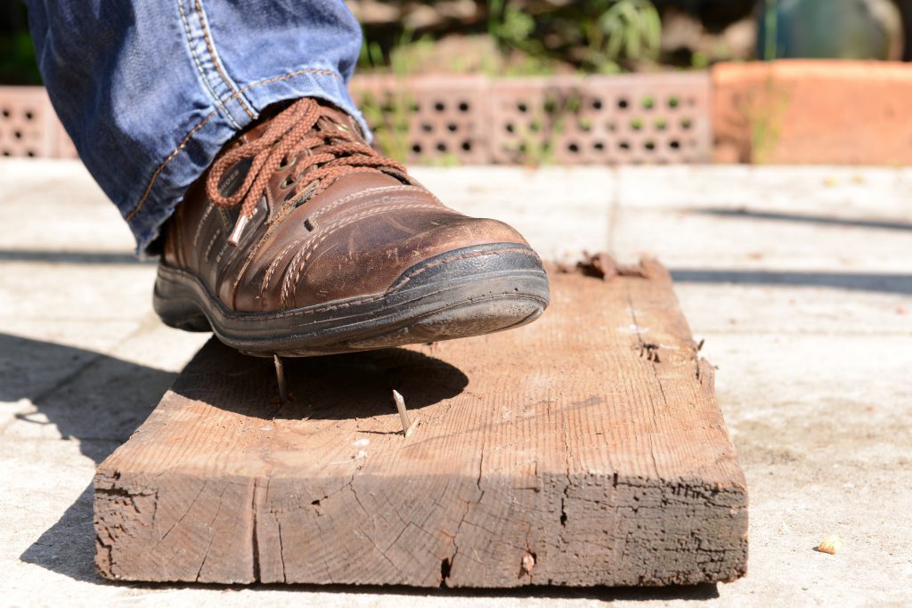 Here is a picture of a construction worker stepping on an exposed nail, a common workplace hazard.